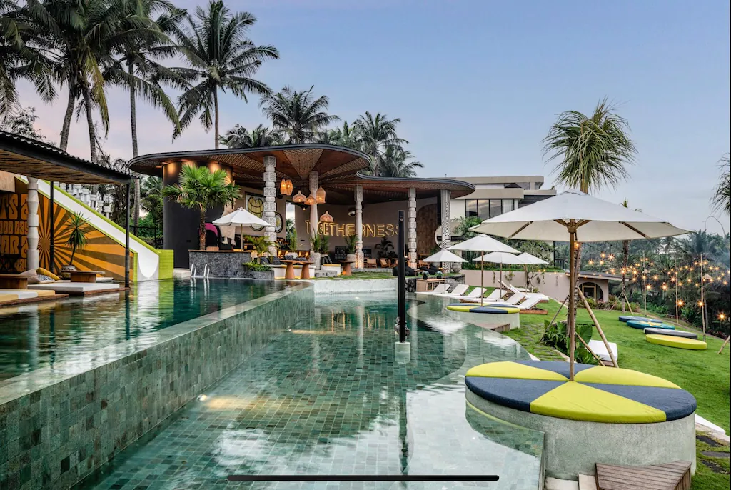 Stylish resort pool with modern tropical design, sun loungers, and palm trees at a luxury retreat in Bali—an ideal destination for vibrant wellness retreats in Bali.