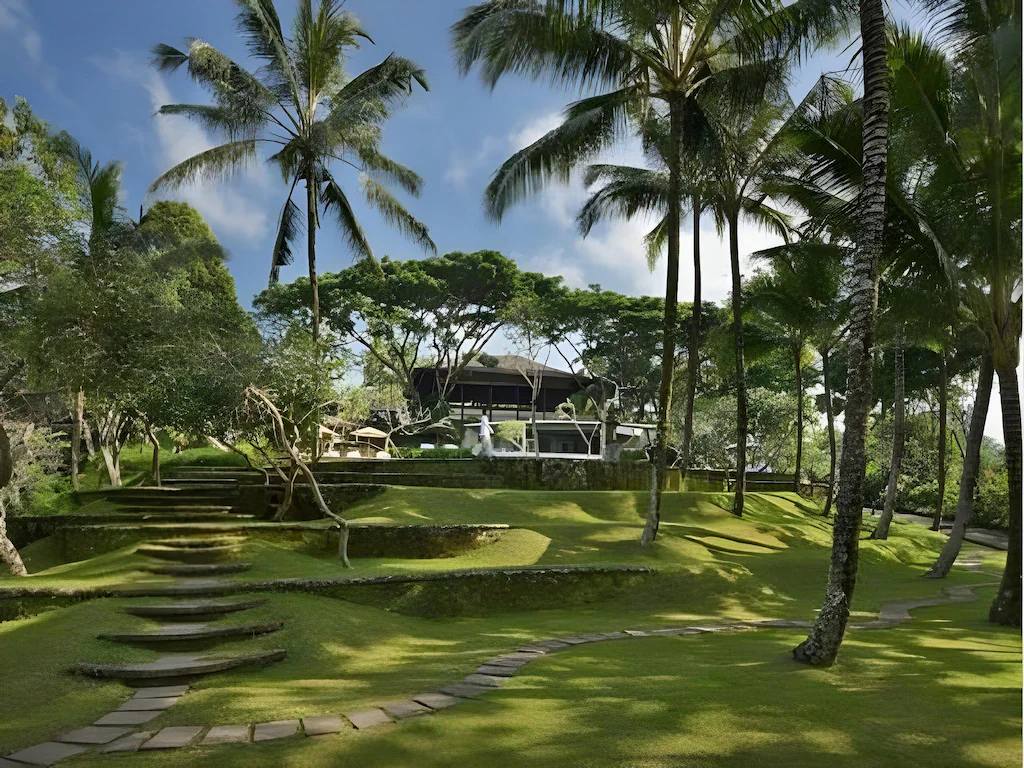 Lush garden pathway leading through tropical palm trees to a tranquil luxury retreat in Bali—perfect for nature-focused wellness retreats in Bali.
