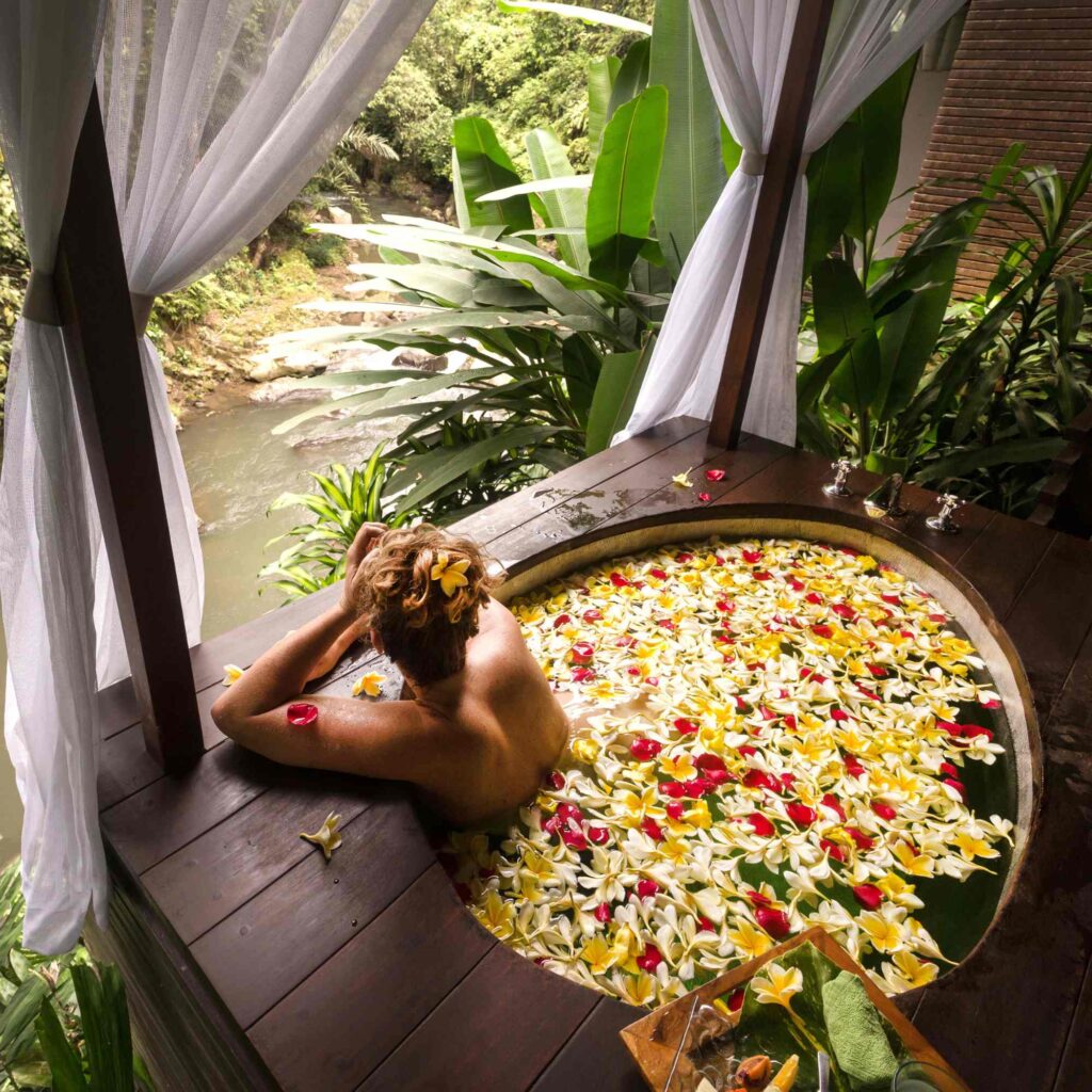  Yellow petals fill a bath with a women relaxing and enjoying the best flower bath in Bali