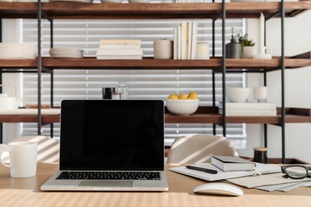 Modern home office workspace with open laptop, coffee mug, and industrial shelving with white subway tile backsplash