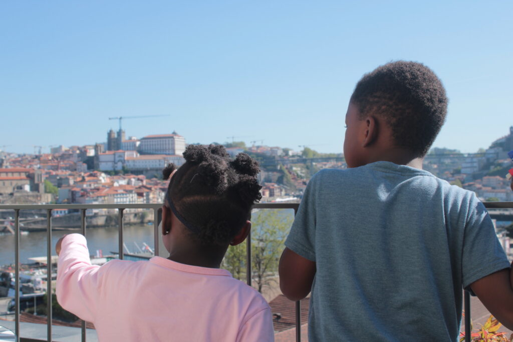Two people overlooking Porto cityscape from viewing platform with river, historic buildings and clear blue sky
