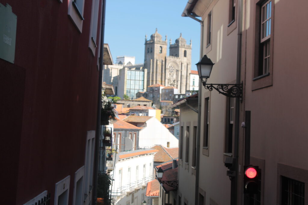 Narrow cobblestone street in Porto with view of Se Cathedral's twin towers and traditional Portuguese buildings