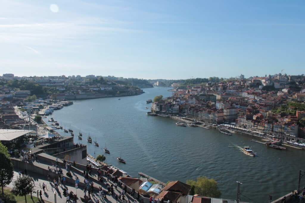 Panoramic view of Porto's Douro River with colorful waterfront buildings, traditional boats, and historic Ribeira district