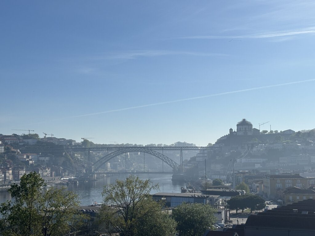 Historic arched bridge spanning river with hillside city buildings and clear blue sky in Porto, Portugal