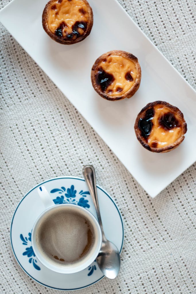 Portuguese pasteis de nata and a ceramic cup of coffee create a delightful food scene.