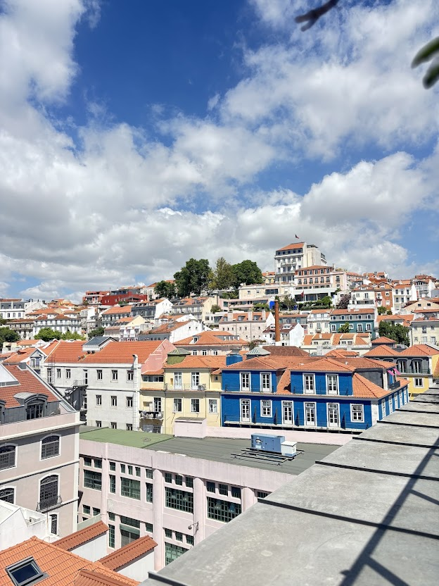 Colorful historic buildings with terracotta roofs in hillside neighborhood under blue sky with white clouds