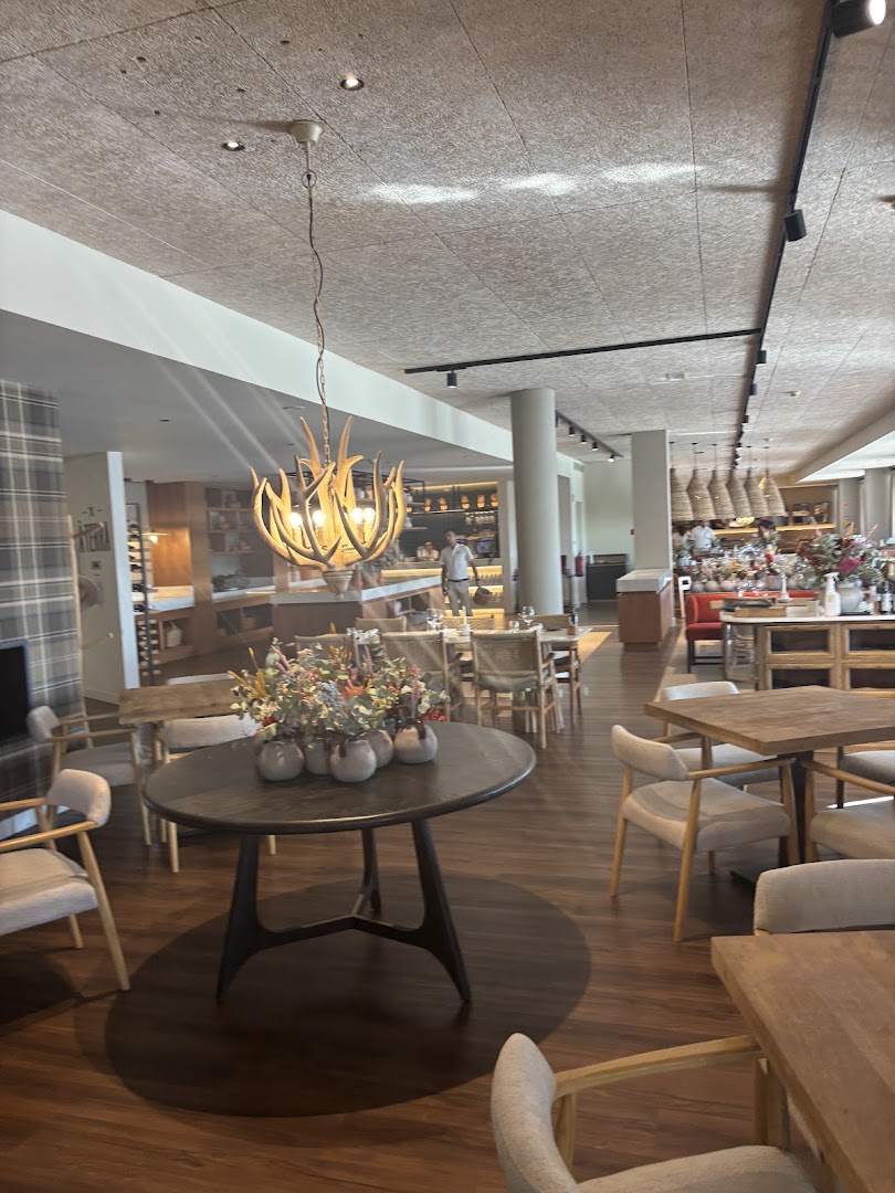 Wooden tables and upholstered chairs inside À Terra restaurant at Octant Évora