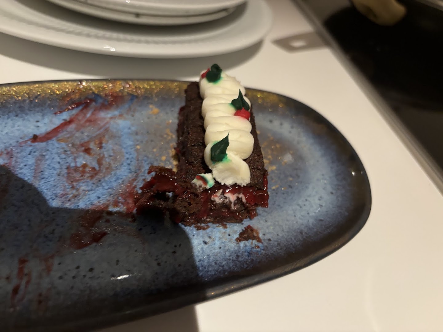 Chocolate dessert with cream and a festive holly decoration on a blue plate