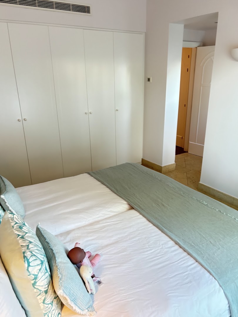 Bed with a pale green cover and built-in wardrobes at Vila Vita Parc.